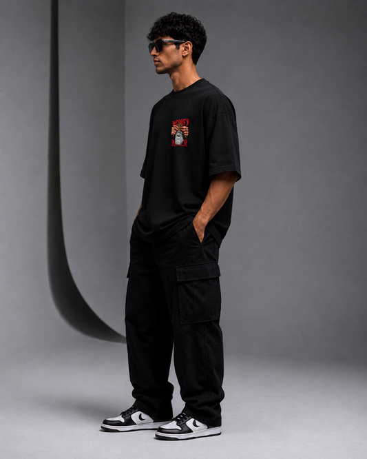 Male model wearing black Oversoul Money Maker Graphic Unisex Oversized T-Shirt side profile view