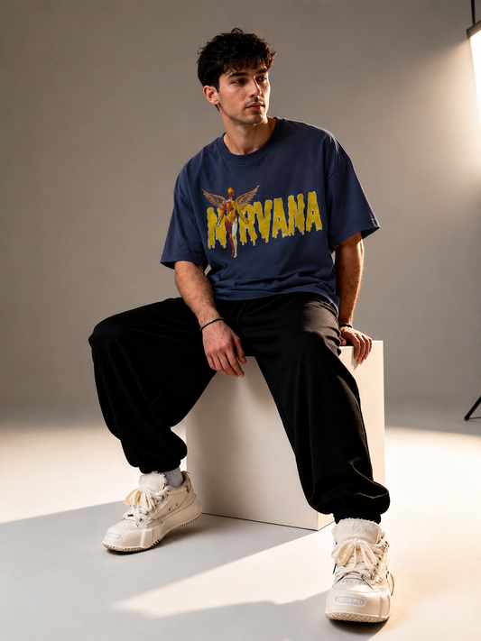 Male model sitting wearing Oversoul Nirvana Graphic Unisex Oversized T-Shirt in deep navy blue